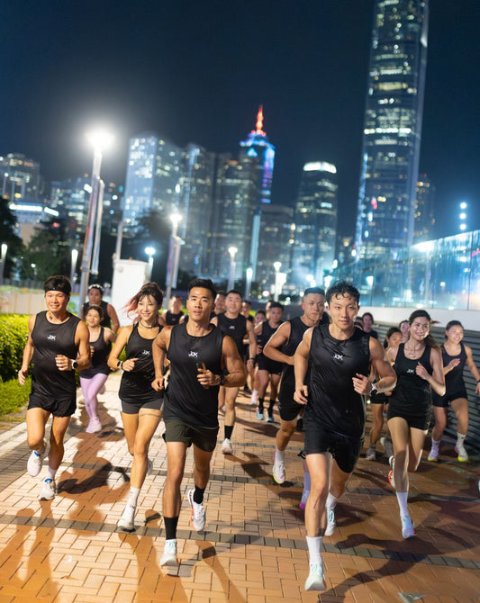 Group of runners (movers) in central and Tamar Park at night with illuminated skyscrapers Hong Kong in the background
